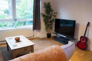 sala de estar con sofá, TV y guitarra en Stylish 2Bed Apt in Leeds - Free Parking!, en Headingley