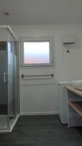 een badkamer met een glazen douche en een raam bij La Villamour avec jacuzzi in Gigean