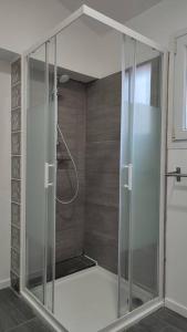 een douche met een glazen deur in de badkamer bij La Villamour avec jacuzzi in Gigean