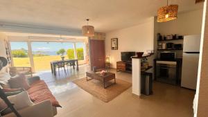 sala de estar con sofá y cocina con mesa en Le Baileys - Spacieux appartement en rez-de-jardin vue lagon, en Marigot