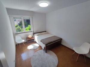 a bedroom with a bed and two chairs and a window at Aconchegante T3 em Telheiras in Lisbon