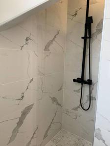 y baño con ducha y paredes de mármol blanco. en Superbe appartement neuf 4 couchages , proche Paris, en Bagnolet