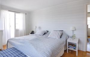 a white bedroom with a large bed with striped sheets at Nice Home In Bovallstrand With 3 Bedrooms And Wifi in Bovallstrand