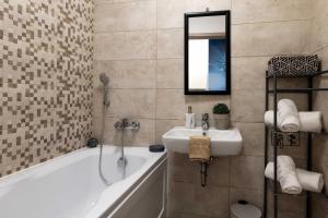 y baño con lavabo, bañera y espejo. en Lido Riviéra 011 Apartman, en Balatonlelle