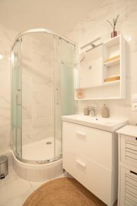 uma casa de banho branca com um chuveiro e um lavatório. em LES DUNES Studio Cosy-Terrasse-Parking -Proche paris em Vitry-sur-Seine