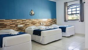 a room with two beds and two couches and a window at Beija Flor Pousada in Ubatuba