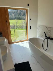 La salle de bains blanche est pourvue d'une grande baignoire et d'une fenêtre. dans l'établissement Tolle Bergvilla im Osterzgebirge, à Kurort Altenberg