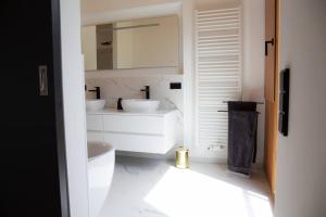 - une salle de bains blanche avec deux lavabos et un miroir dans l'établissement Tolle Bergvilla im Osterzgebirge, à Kurort Altenberg