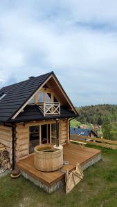 Cette cabane en rondins dispose d'une grande terrasse et d'une grande fenêtre. dans l'établissement Domek na Kleninie z gorącą balią, à Kamienica