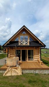 Cette cabane en rondins dispose d'une grande fenêtre et d'une terrasse en bois. dans l'établissement Domek na Kleninie z gorącą balią, à Kamienica