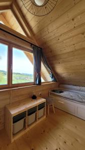 a log cabin with a bed and two windows at Domek na Kleninie z gorącą balią in Kamienica