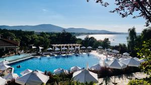 a large swimming pool with umbrellas and a lake at Cozy Home Santa Marina in Sozopol