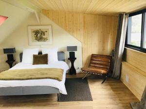 ein Schlafzimmer mit einem Bett und einem Stuhl in der Unterkunft Clairseine in Tournedos-sur-Seine