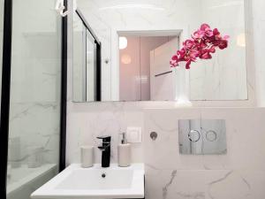 un baño blanco con lavabo y un jarrón de flores en Apartment Sophie 3 rooms, 2 bathrooms, 8 persons, en Cracovia
