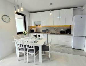 cocina blanca con mesa blanca y sillas en Apartment Sophie 3 rooms, 2 bathrooms, 8 persons, en Cracovia