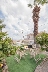 une terrasse avec 2 chaises, une table et un palmier dans l'établissement Inconceptual apartment, à Paradeísion