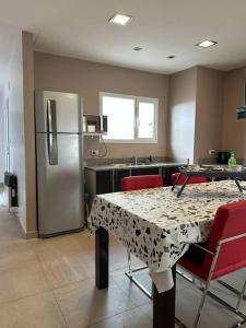 a kitchen with a table and a stainless steel refrigerator at Estepa Apart 1B calidad y confort in Comodoro Rivadavia