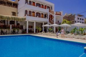 un hombre y un niño parados junto a una piscina frente a un edificio en Hotel Curasi en Ica