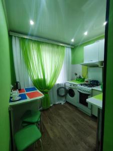 cocina verde con mesa y fogones en Апартаменты 2-х комнатные в Степногорске en Stepnogorsk