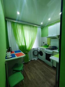 a green kitchen with a table and a stove at Апартаменты 2-х комнатные в Степногорске in Stepnogorsk