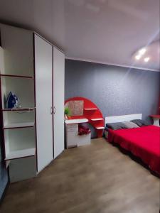 1 dormitorio con cama roja y armario blanco en Апартаменты 2-х комнатные в Степногорске en Stepnogorsk