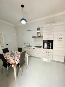 une cuisine avec une table et des chaises et une cuisine avec des placards blancs dans l'établissement La Maison De Rose, à Torre Annunziata