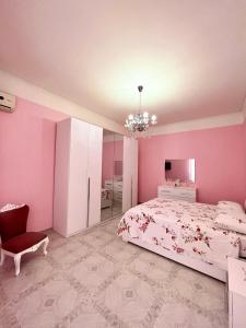 a bedroom with pink walls and a bed and a chair at La Maison De Rose in Torre Annunziata