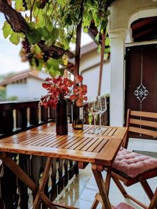 Apartment Kolodvor في Dornberk: طاولة خشبية مع كؤوس نبيذ وزهور على شرفة