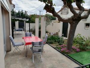 un patio con mesa roja y sillas en La maison de 6Fran appartement 1 calme et spacieux ambiance familiale, en Valros