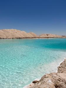 a blue body of water with mountains in the background at Hidden place in Siwa