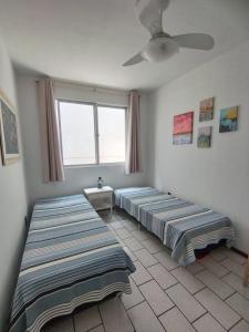 2 Betten in einem Zimmer mit Fenster in der Unterkunft Quarto em apartamento da Sandra in Balneário Camboriú