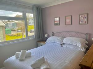 a bedroom with a bed with white sheets and a window at Pass the Keys Seaside Escape Freshwater East in Pembroke