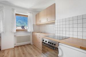 Wohnung Hochstaufen في انزل: مطبخ مع موقد فرن علوي بجوار نافذة