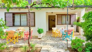 a patio with colorful chairs and tables in front of a house at Lourantos Studios & Apartments in Vathi