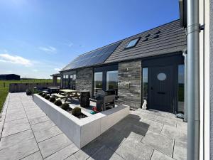 a house with a patio with a solar roof at Flotnar Hús - Ensuite Rooms in Keiss