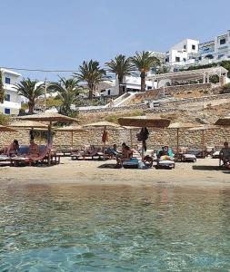 un gruppo di persone seduti su una spiaggia con ombrelloni di Grannys Luxury Villas a Karpathos