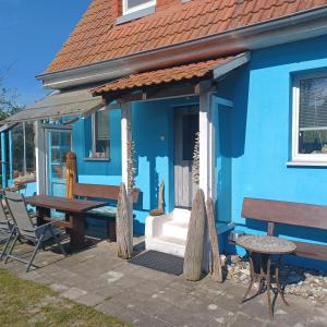une maison bleue avec une table et un banc dans l'établissement Ferienhaus Dünenhaus, à Dierhagen