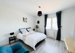 ein weißes Schlafzimmer mit einem Bett und einem blauen Stuhl in der Unterkunft Maison Léon in Ychoux