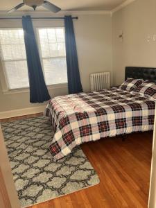 a bedroom with a bed with a plaid blanket and two windows at Secret Oasis In The Heart Of Hartford in Hartford