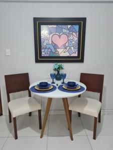 a dining room table with two chairs and a heart painting at Manaíra Flat 206 Em frente ao shopping Manaíra in João Pessoa