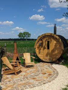 uma cabana de madeira redonda com 2 cadeiras e um barril em Natures-Rest Wielen em Wielen