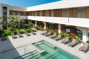 una vista esterna di un edificio con piscina e sedie di Limen Wellness Hotel & Spa a Campofelice di Roccella