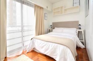 een witte slaapkamer met een bed en een groot raam bij Luxury Cañitas hermoso monoambiente in Buenos Aires