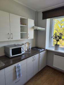 una cucina con armadi bianchi e un forno a microonde su un bancone di Station street apartments a Sigulda