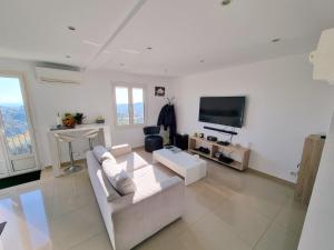 a white living room with a white couch and a tv at 2 pièces d’exception vue Mer in Vence