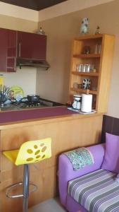 une cuisine avec un canapé violet à côté d'un comptoir dans l'établissement Studio meublé, à Riffiene