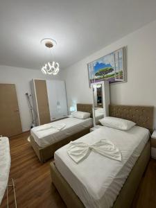 a bedroom with two beds and a chandelier at Cosy 2BR Apartment near Tirana Airport - SELF CHECK-IN 24hr in Tirana