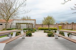 un giardino con due panchine di fronte a un edificio di De Pastorie Diksmuide a Diksmuide