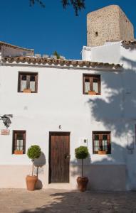 a white building with a wooden door and potted plants at Acogedora casa rural en Olvera ,La Morada in Olvera
