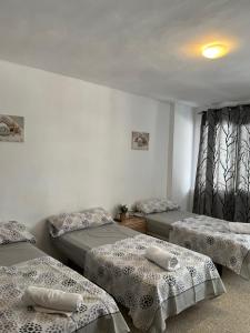 Habitación con 3 camas y ventana en pensión La Parada en Alicante